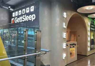 Beleuchteter GettSleep-Schriftzug mit Service-Symbolen neben dem Eingang der Sleep Lounge am Flughafen Adolfo Suárez Madrid-Barajas (T4S)